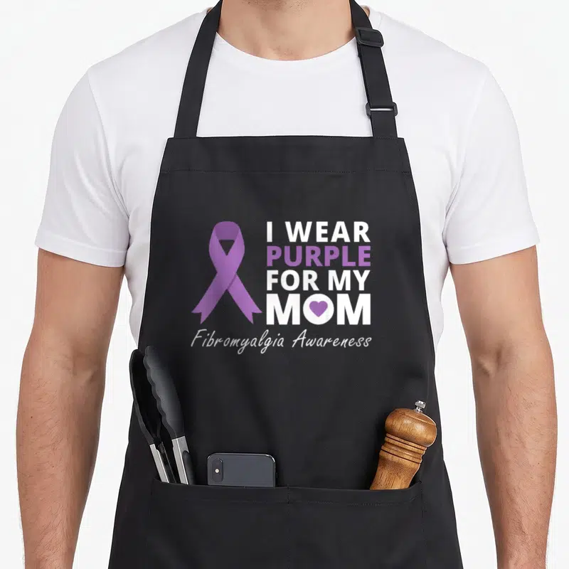 Fibromyalgia i love production apron - Purple awareness ribbon next to stacked white text reading I Wear Purple For My — shown on a black cotton canvas apron against a white background