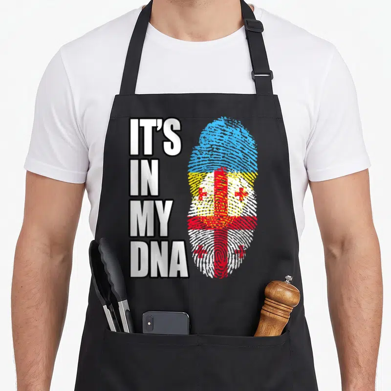 Georgian heritage ukrainian aprons - Stacked text IT'S IN MY DNA beside fingerprint filled with Georgian flag colors — shown on a black cotton canvas apron against a white background