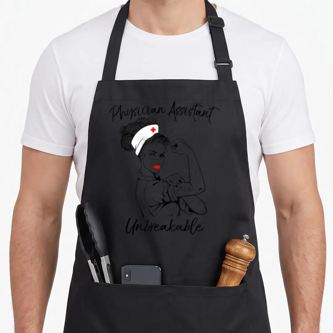 Physician doctor apron - Cartoon woman flexing arm between Physician Assistant and Unbreakable text with red cross cap — shown on a black cotton canvas apron against a white background
