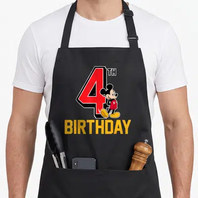 Funny 4th birthday apron - Large red number 4 with standing Mickey Mouse and yellow BIRTHDAY text — shown on a black cotton canvas apron against a white background
