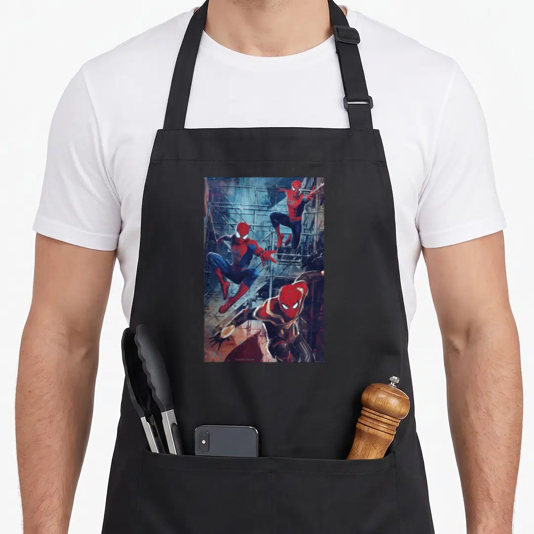 Spider jump apron - Three Spider-Men leaping in red blue grey suits against scaffolding background — shown on a black cotton canvas apron against a white background