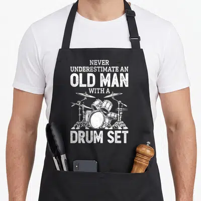 Drummer papa pigeon apron - Distressed white text and drum kit illustration on grey background — shown on a black cotton canvas apron against a white background