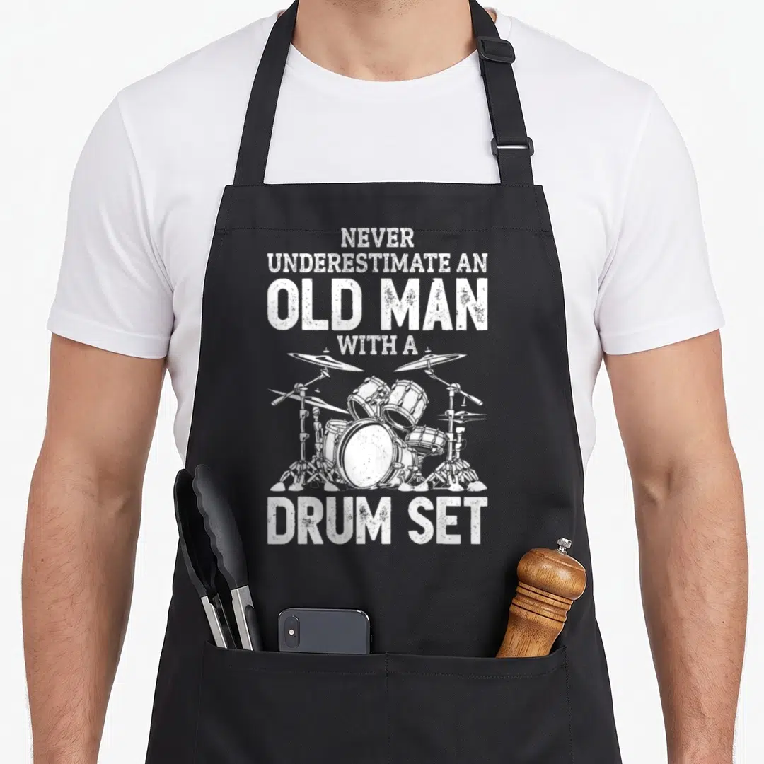 Drummer papa pigeon apron - Distressed white text and drum kit illustration on grey background — shown on a black cotton canvas apron against a white background