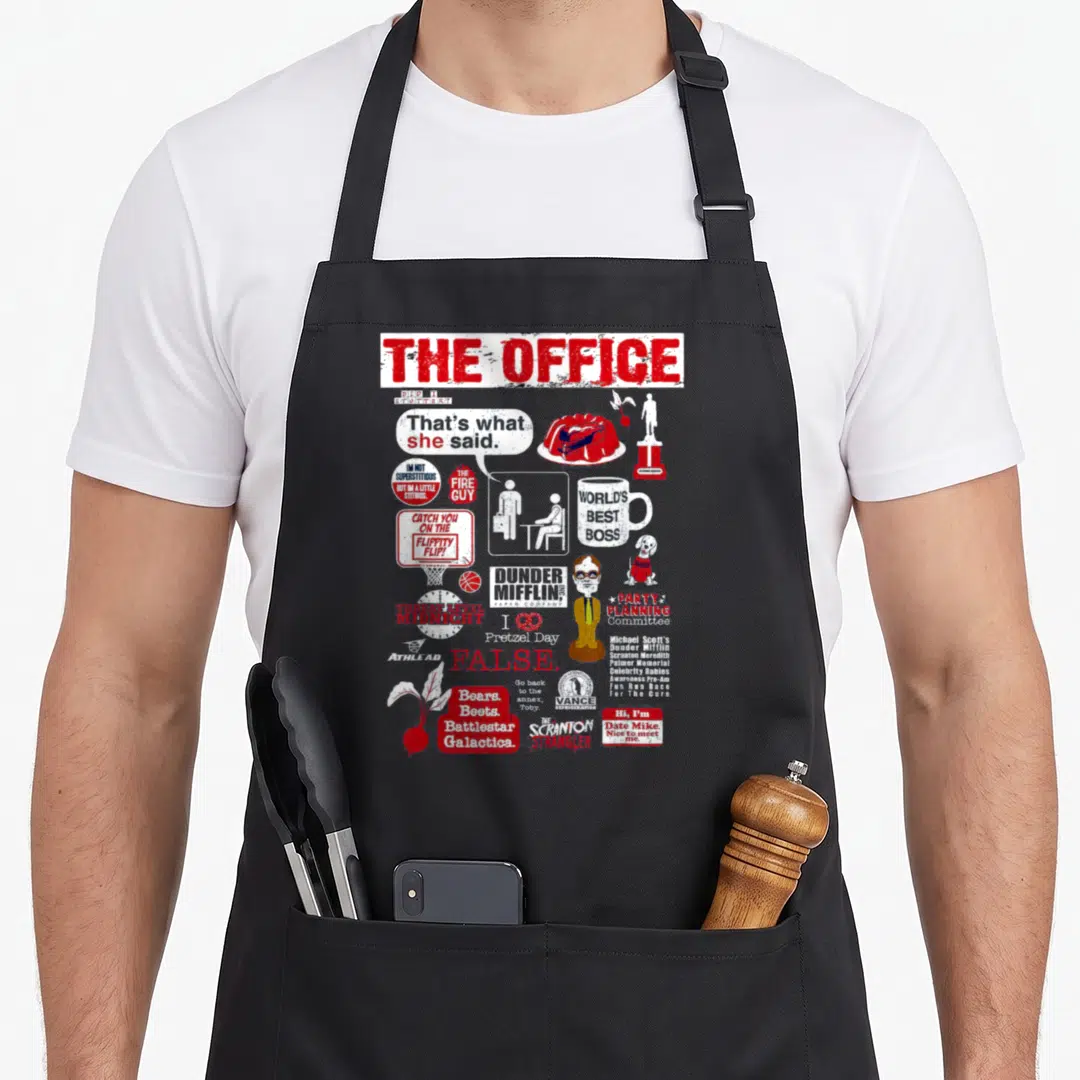 Retro food novelty apron - The Office quote collage with That's what she said and Bears Beets Battlestar Galactica text — shown on a black cotton canvas apron against a white background