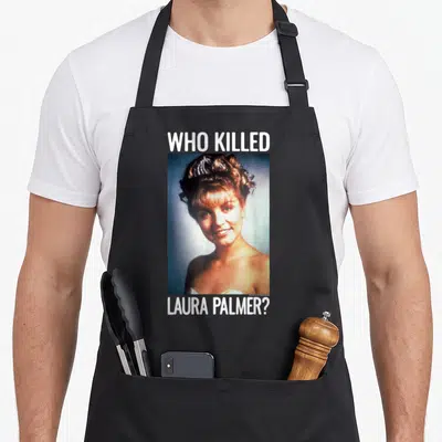 Killed twin peaks apron - Photo of a woman between white text reading WHO KILLED LAURA PALMER on a black background — shown on a black cotton canvas apron against a white background