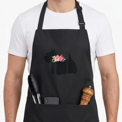 Scottish terrier dog apron - Black dog silhouette facing left with pink watercolor flowers on chest — shown on a black cotton canvas apron against a white background