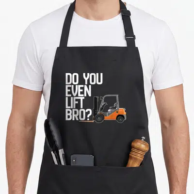 Even forklift apron - Stacked white text DO YOU EVEN LIFT BRO next to orange cartoon forklift — shown on a black cotton canvas apron against a white background