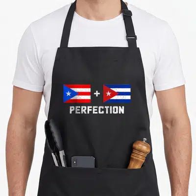 Perfection pride apron - Two flags with red white blue stripes and stars separated by a plus sign above the word — shown on a black cotton canvas apron against a white background