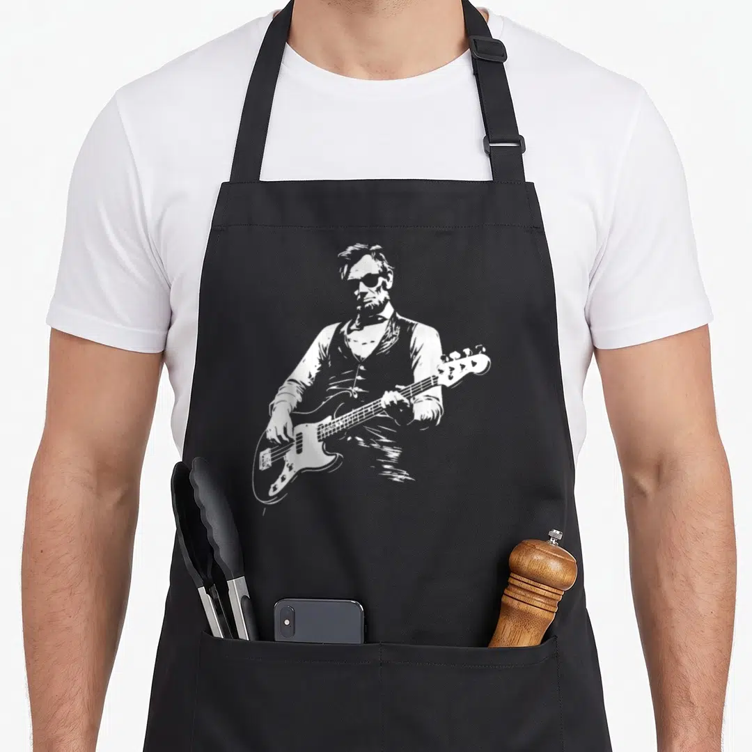 President abraham playing guitar apron - White line art of a bearded man playing a four-string bass guitar on a black — shown on a black cotton canvas apron against a white background