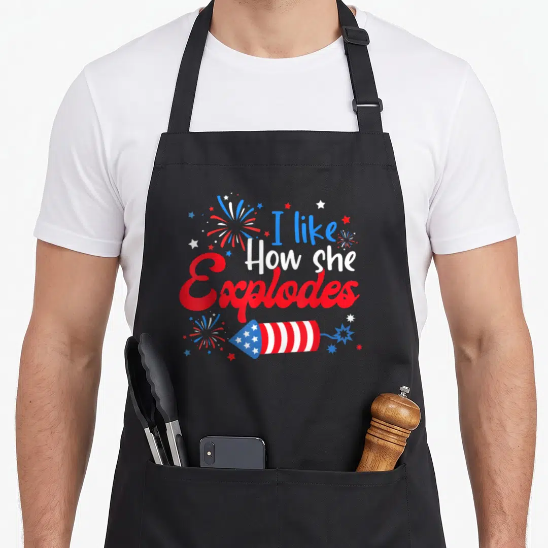 Couple 4th of july apron - Stacked red white blue text above cartoon firework rocket with scattered starbursts — shown on a black cotton canvas apron against a white background