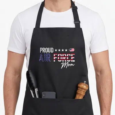 Flag proud us aprons - Stacked text PROUD AIR FORCE Mom with flag fill, four stars, and US flag dog tag — shown on a black cotton canvas apron against a white background
