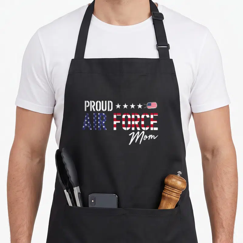 Flag proud us aprons - Stacked text PROUD AIR FORCE Mom with flag fill, four stars, and US flag dog tag — shown on a black cotton canvas apron against a white background