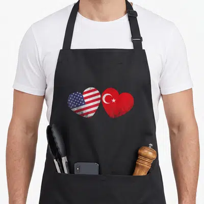 Turkish patriotic american flag apron - Two hearts side-by-side filled with USA and Turkey flags in distressed red — shown on a black cotton canvas apron against a white background