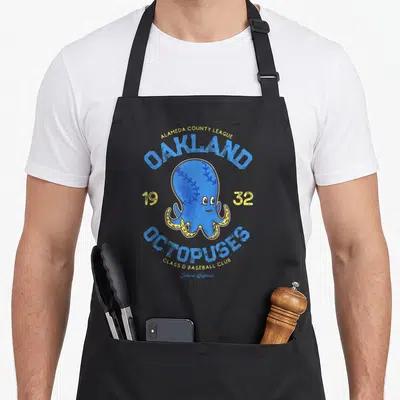 Octopuse baseball apron - Blue octopus mascot with baseball stitching surrounded by Oakland Octopuses 1932 text — shown on a black cotton canvas apron against a white background