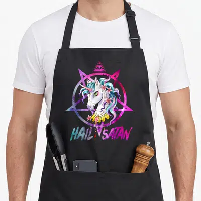 Hail rainbow apron - Cartoon unicorn head inside pink pentagram with HAIL SATAN text and eye of providence — shown on a black cotton canvas apron against a white background