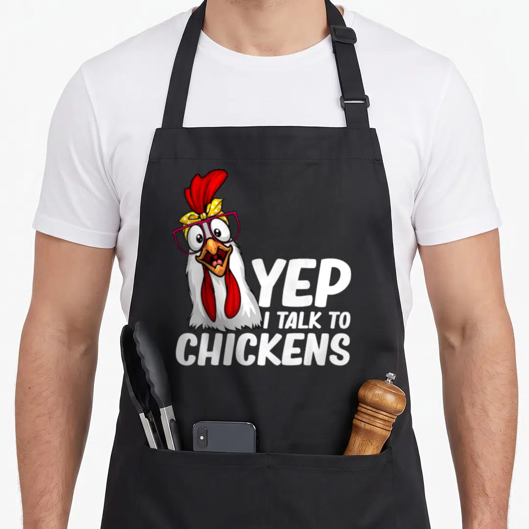 Cute farmer chicken apron - Cartoon white chicken with pink glasses and YEP I TALK TO CHICKENS text — shown on a black cotton canvas apron against a white background