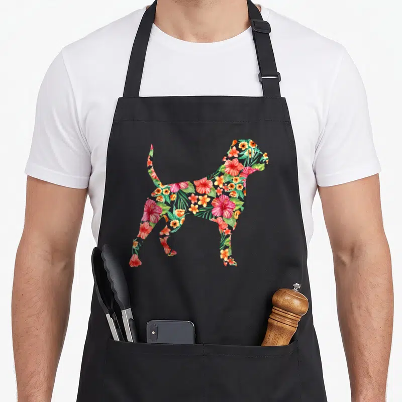 Bulldog floral apron - Dog silhouette filled with red green orange hibiscus leaves watercolor pattern on black — shown on a black cotton canvas apron against a white background