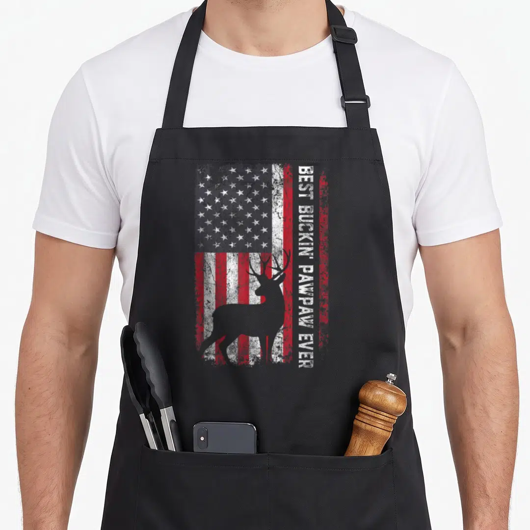 Deer father day apron - Best Buckin Pawpaw Ever text beside deer silhouette on distressed flag — shown on a black cotton canvas apron against a white background