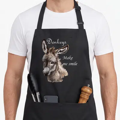 Donkey animal apron - Realistic donkey head portrait with white cursive text Donkeys Make me smile — shown on a black cotton canvas apron against a white background