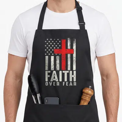 Faith fear american flag apron - Red cross over distressed grey and white stars and stripes with stacked FAITH — shown on a black cotton canvas apron against a white background