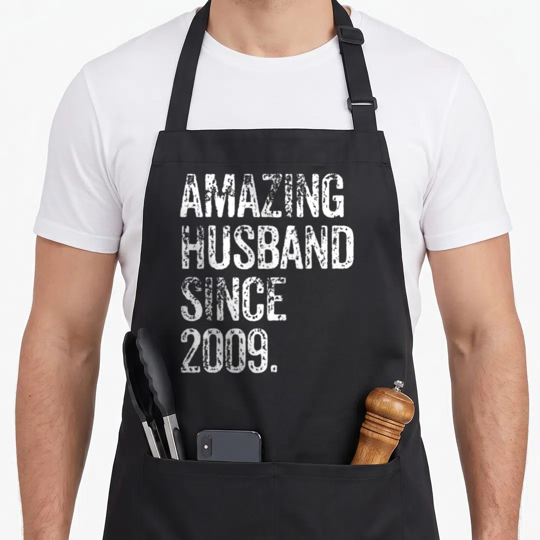 Amazing wedding aprons - White stacked text reading amazing husband since 2009 on a black background — shown on a black cotton canvas apron against a white background