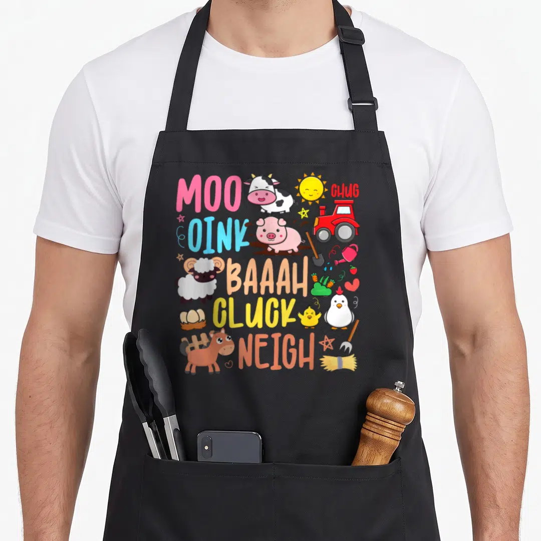 Sound farm apron - Cartoon cow pig sheep chicken horse tractor with sound words MOO OINK BAAAH CLUCK NEIGH CHUG — shown on a black cotton canvas apron against a white background