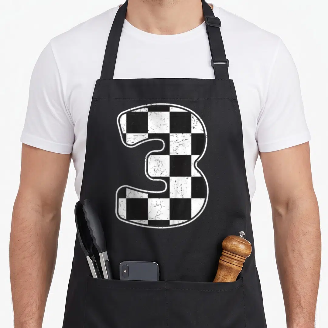 Three car apron - Distressed black and white checkered number 3 graphic — shown on a black cotton canvas apron against a white background