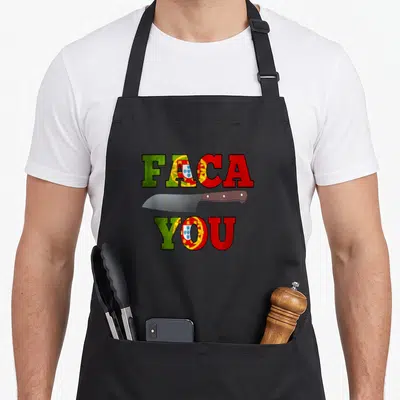 Faca portuguese apron - FACA YOU text with horizontal knife in green red yellow silver flag colors — shown on a black cotton canvas apron against a white background