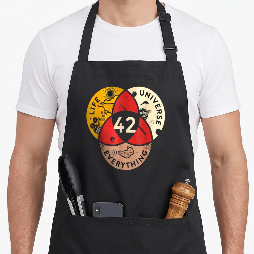 Answer science apron - Heart graphic with 42, Life Universe Everything, and Oh No Not Again in yellow red beige — shown on a black cotton canvas apron against a white background