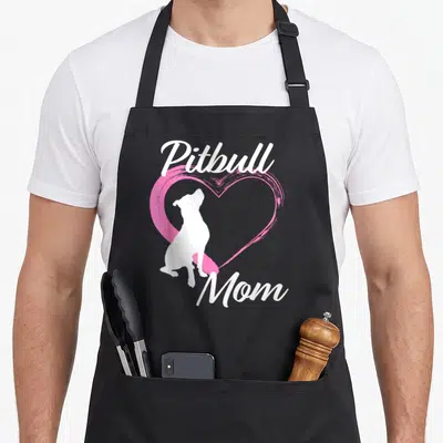 Funny pitbull apron - White pitbull silhouette inside pink heart with Pitbull Mom text — shown on a black cotton canvas apron against a white background