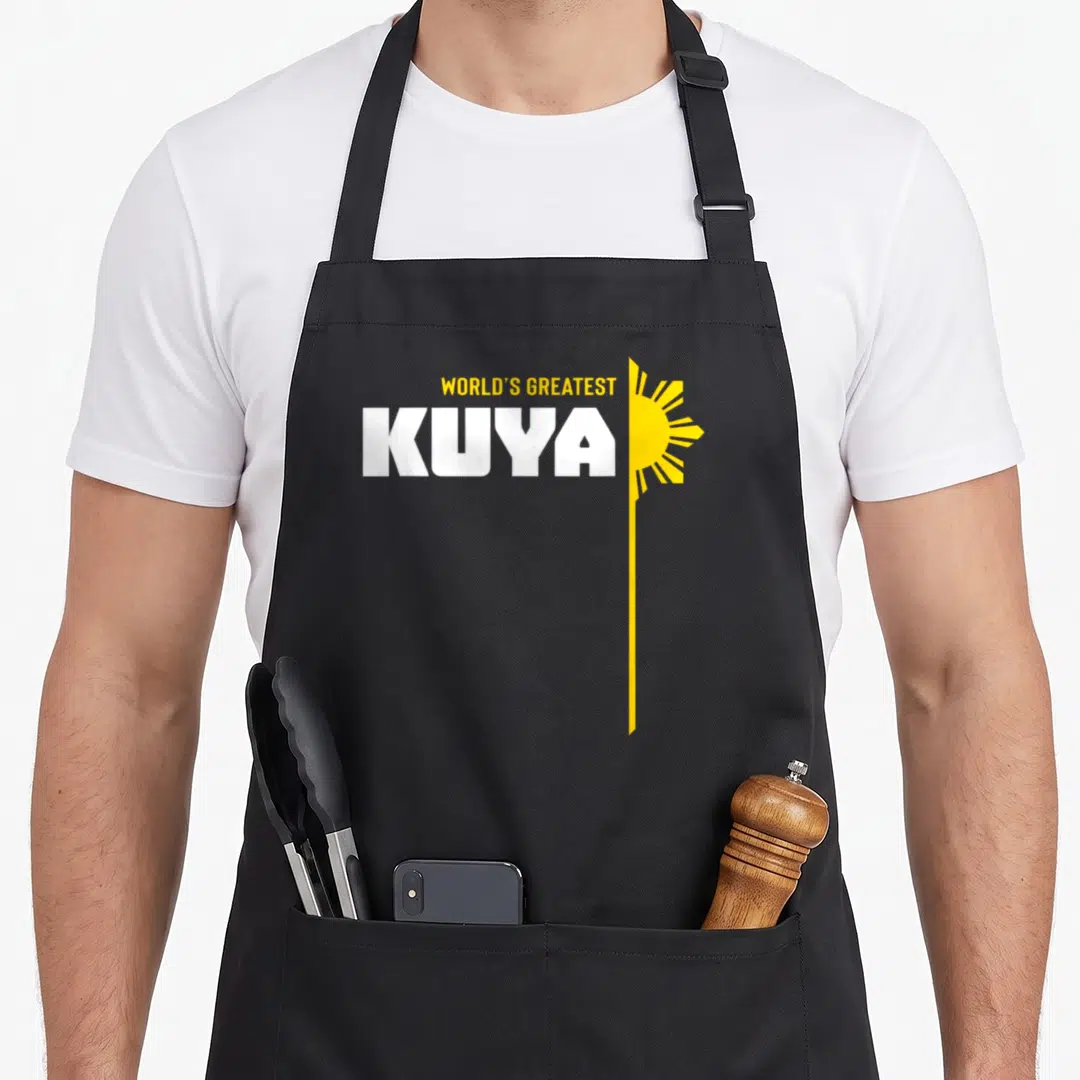 Kuya worlds greatest dad apron - WORLD'S GREATEST KUYA text with yellow sun and vertical line — shown on a black cotton canvas apron against a white background