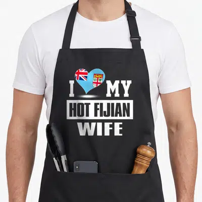 Fijian wife apron - White text I MY HOT FIJIAN WIFE with a blue red and white flag heart — shown on a black cotton canvas apron against a white background