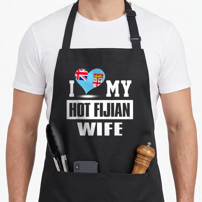 Fijian wife apron - White text I MY HOT FIJIAN WIFE with a blue red and white flag heart — shown on a black cotton canvas apron against a white background