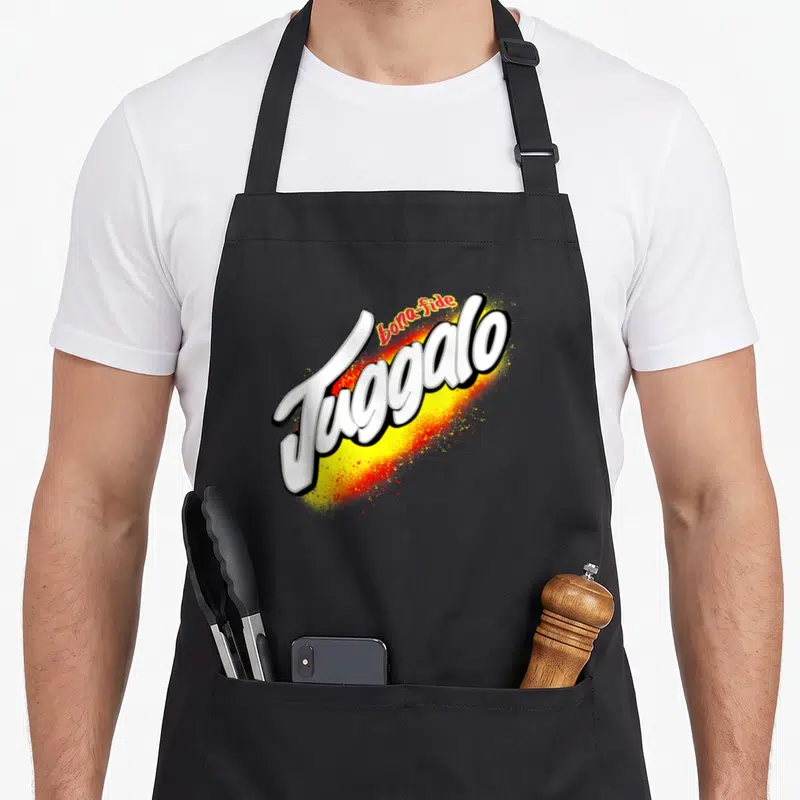 Wicked tag apron - bona-fide Juggalo white text over yellow and red spray paint splatter graphic — shown on a black cotton canvas apron against a white background