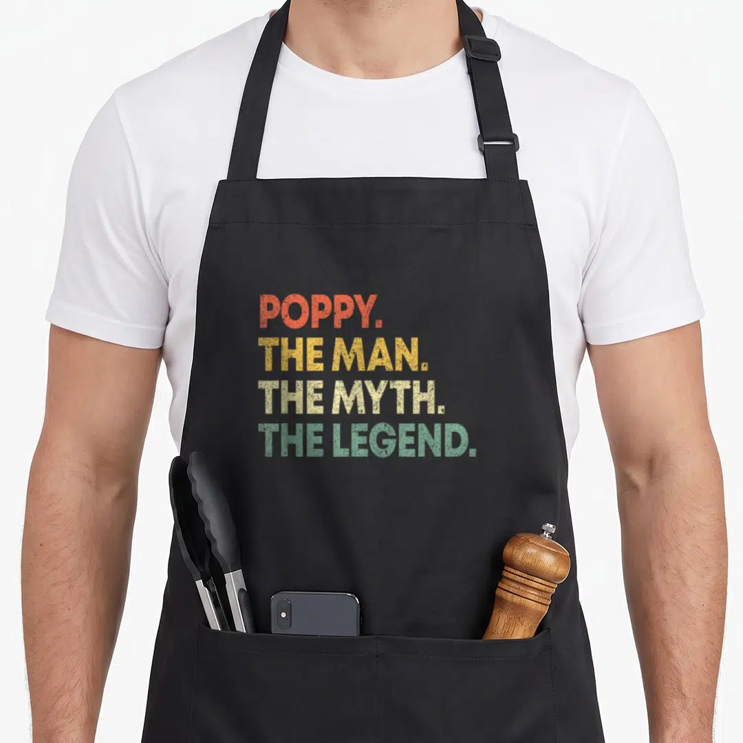 Poppy grandpa apron - Stacked text POPPY THE MAN THE MYTH THE LEGEND in red yellow beige green distressed font — shown on a black cotton canvas apron against a white background