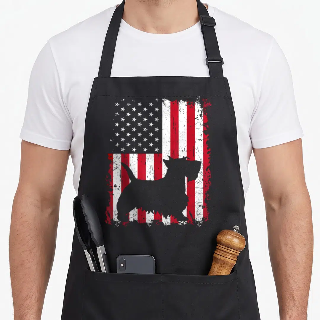 Scottish 4th of july apron - Grey terrier silhouette standing in front of a distressed red white and blue American flag — shown on a black cotton canvas apron against a white background