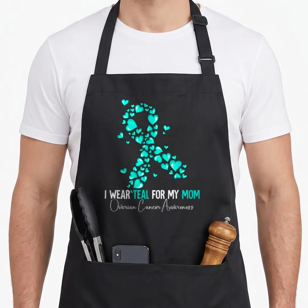 Cute ovarian cancer awareness apron - Teal heart ribbon forming awareness symbol above 'I WEAR TEAL FOR MY MOM' text — shown on a black cotton canvas apron against a white background