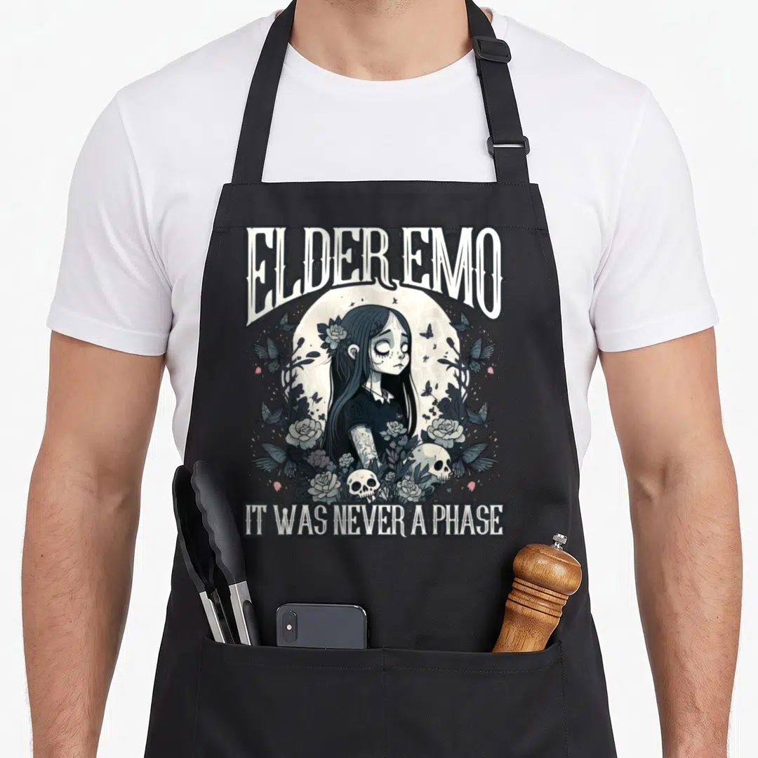 Alt emo apron - Elder Emo text and cartoon girl with roses, skulls, and butterflies in grey and black tones — shown on a black cotton canvas apron against a white background