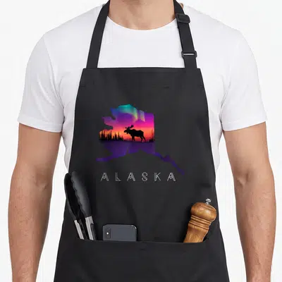 Elk alaska apron - Alaska map silhouette with moose, aurora borealis, and white geometric text — shown on a black cotton canvas apron against a white background