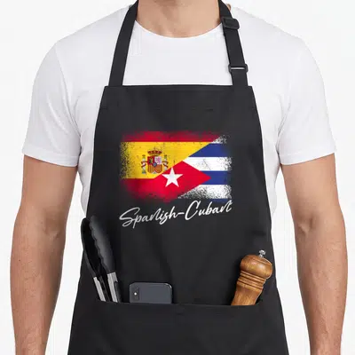 Heritage spanish aprons - Merged Spanish Cuban flags with white script text and distressed texture — shown on a black cotton canvas apron against a white background