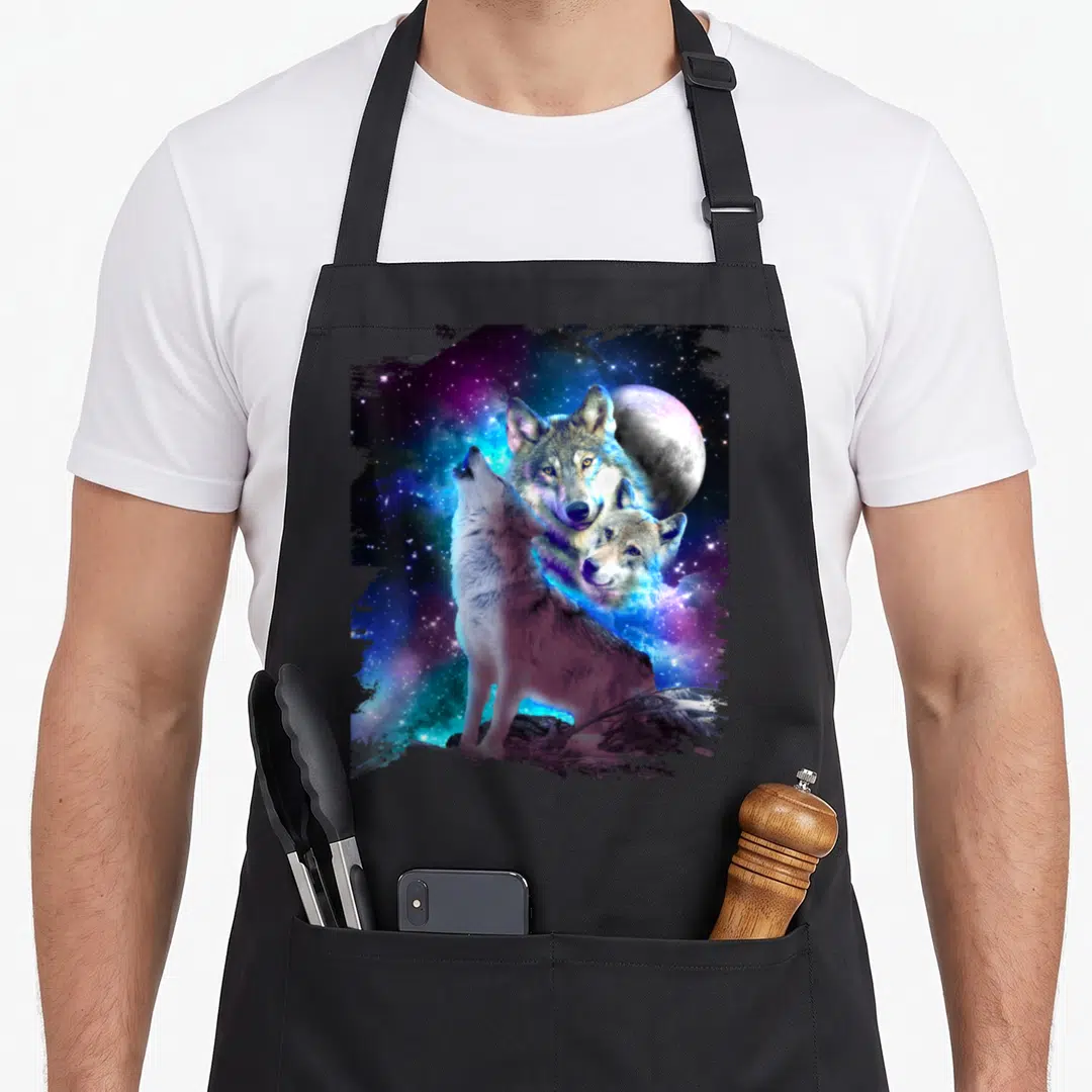 Cosmic family aprons - Three realistic wolves against blue purple grey and white cosmic background with moon — shown on a black cotton canvas apron against a white background