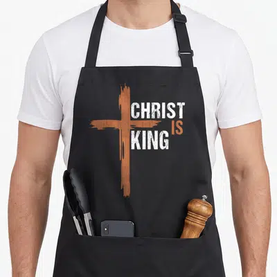 Christ christian king of the grill apron - Orange distressed cross with white CHRIST IS KING text — shown on a black cotton canvas apron against a white background