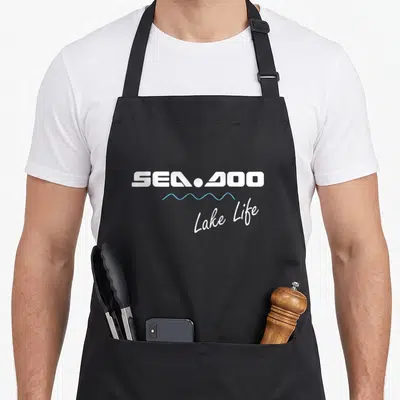 Wave summer life apron - SEA-DOO text above blue wave line and Lake Life script — shown on a black cotton canvas apron against a white background