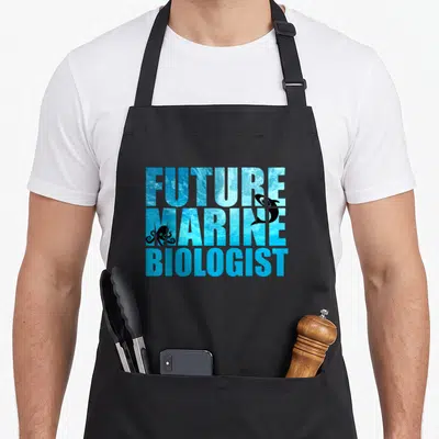 Future marine science apron - Stacked text filled with blue ocean water and black shark and octopus silhouettes — shown on a black cotton canvas apron against a white background