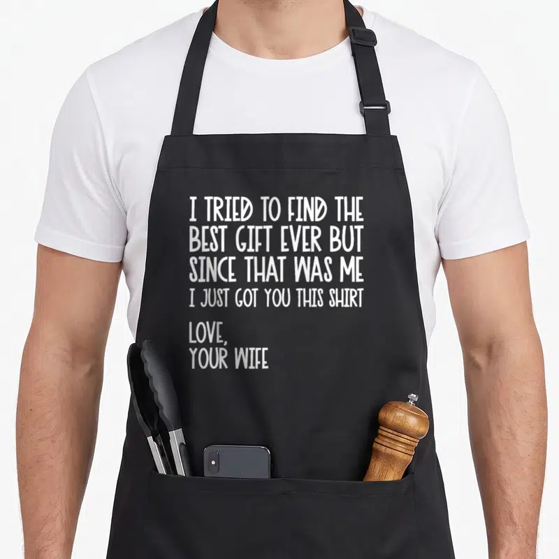 Tried husband apron - White text reading I Tried to Find the Best Gift Ever but since that was me I just got you this — shown on a black cotton canvas apron against a white background