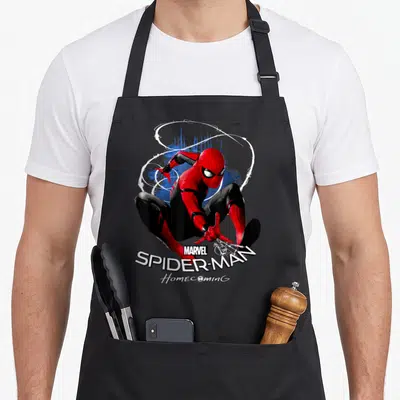 Homecoming web theme apron - Spider-Man crouching in red and black suit with white web swirls and stacked MARVEL — shown on a black cotton canvas apron against a white background