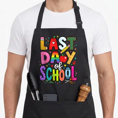 Student classroom aprons - Stacked text LAST DAY of SCHOOL formed by pencils apples and ruler in cartoon style — shown on a black cotton canvas apron against a white background