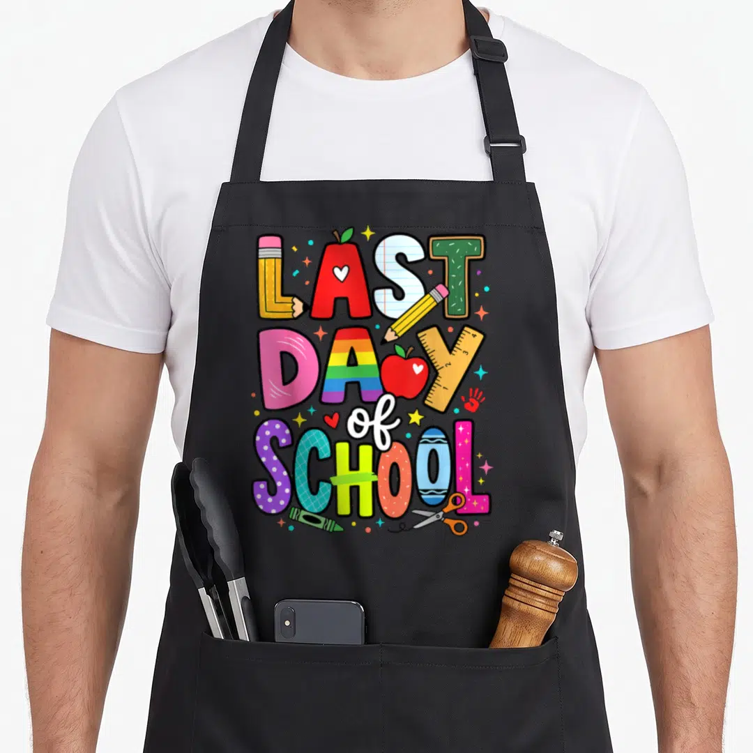 Student classroom aprons - Stacked text LAST DAY of SCHOOL formed by pencils apples and ruler in cartoon style — shown on a black cotton canvas apron against a white background
