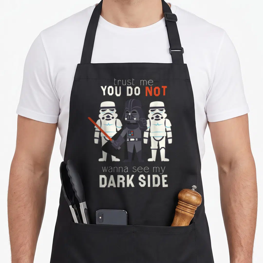 Hope cartoon apron - Darth Vader and two Stormtroopers with sarcastic text in white grey red and blue — shown on a black cotton canvas apron against a white background