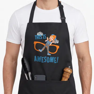 Blippi glass apron - Cartoon boy leaning on orange glasses with THIS IS AWESOME! text and white clouds — shown on a black cotton canvas apron against a white background